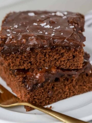 Two slices of chocolate cake on a white plate.