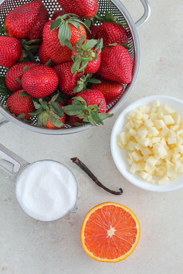 Ingredients for making strawberry jam - strawberries, apples, sugar, orange, vanilla.
