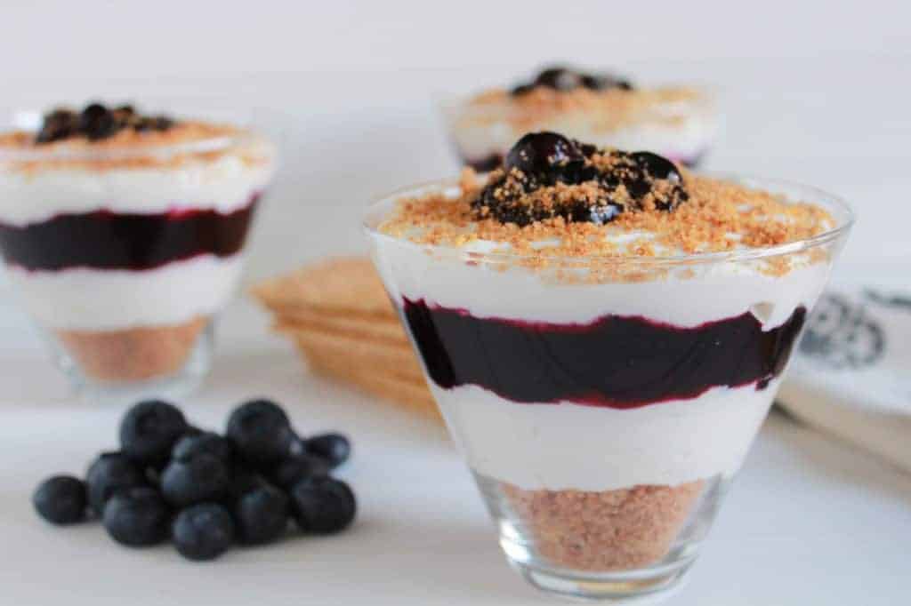 Triangular glass filled with blueberry cheesecake. 