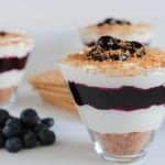 Triangular glass filled with blueberry cheesecake.