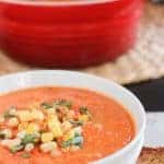 Tomato soup in a white bowl topped with corn.