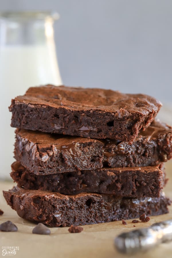 Stack of four brownies on parchment paper.