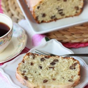 Slice of cake on a white plate with a cup of coffee.