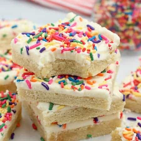 Stack of sugar cookies bars topped with frosting and sprinkles.