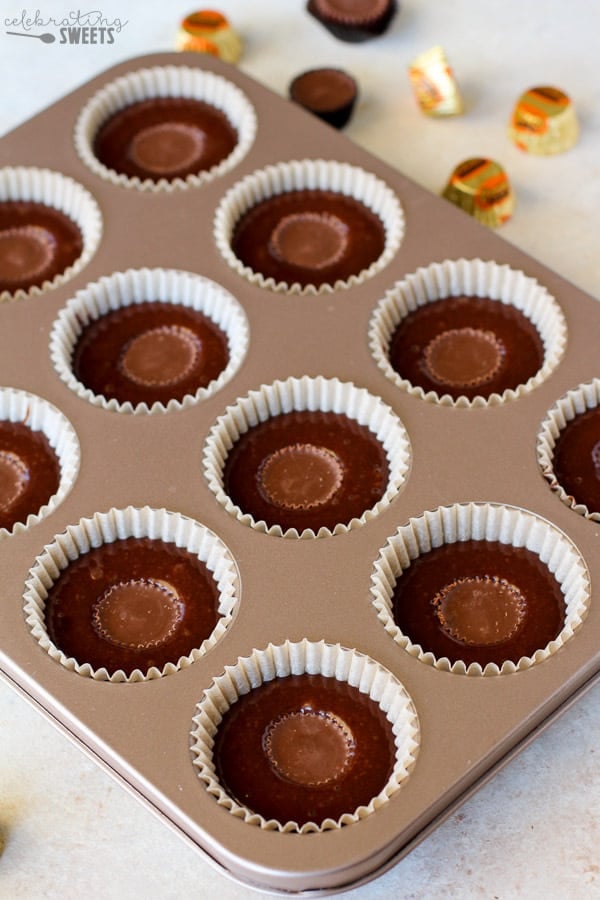 Cake batter in a muffin tin with a peanut butter cup on top.