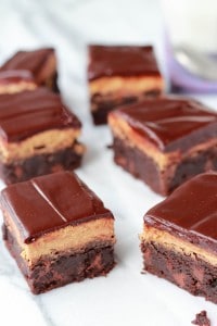 Brownies with brown frosting on a marble board.