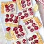 Slices of Lemon Tart topped with Raspberries on a White Platter.