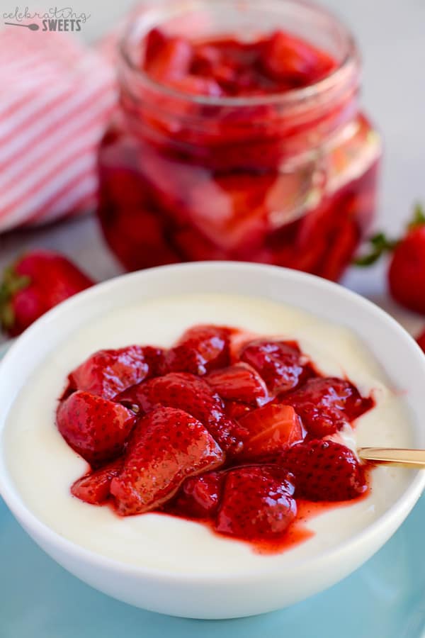 Strawberry sauce on top of yogurt in a white bowl on a blue plate.