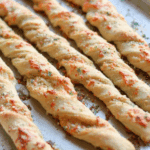 Five twisted breadsticks on a baking sheet.