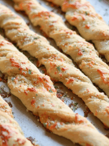 Five twisted breadsticks on a baking sheet.