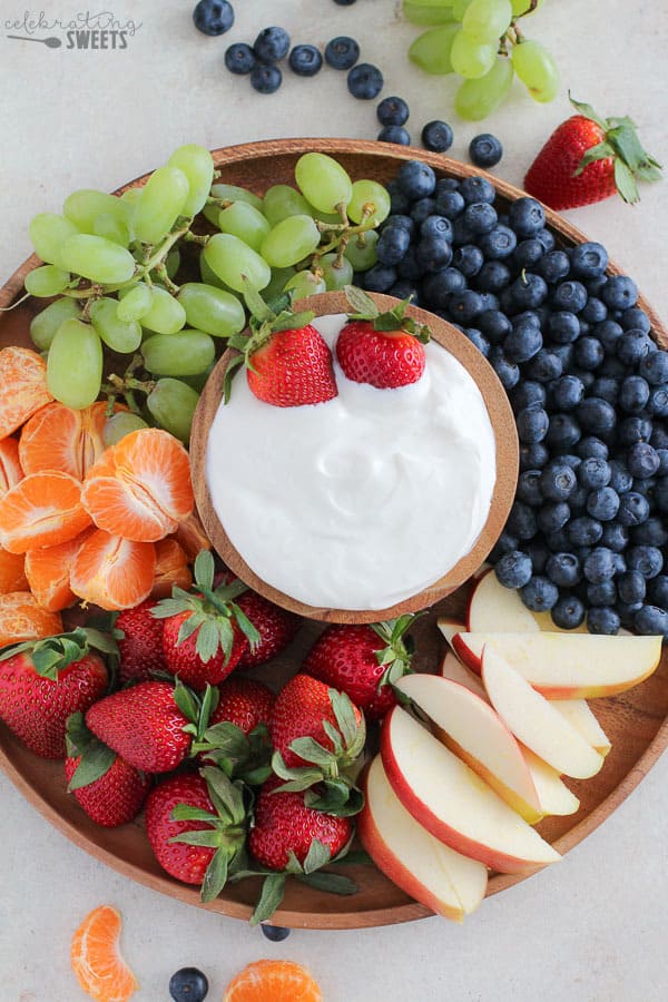 Platter of fruit with a bowl of dip in the center.