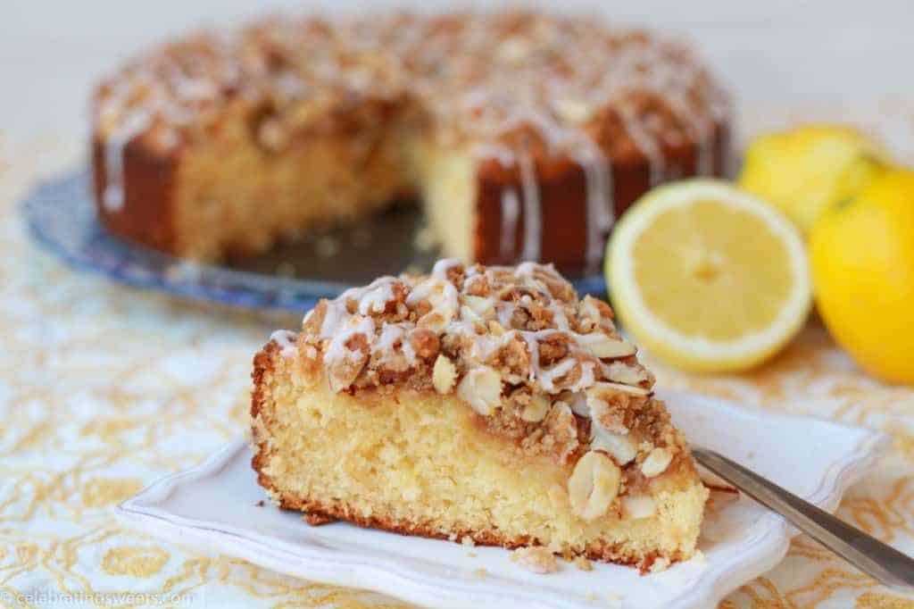 Slice of lemon coffee cake on a white plate on a yellow placemat.