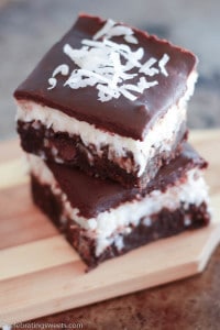 Two coconut brownies on a wooden board.