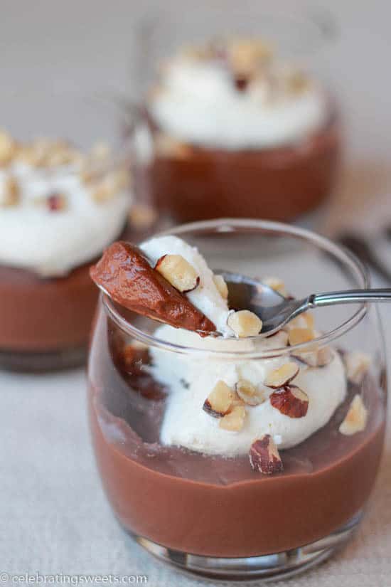 Glass filled with pudding and whipped cream and garnished with nuts.