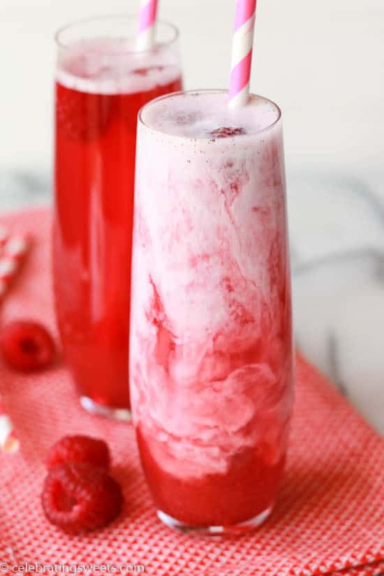Two glasses filled with red soda and a splash of cream.