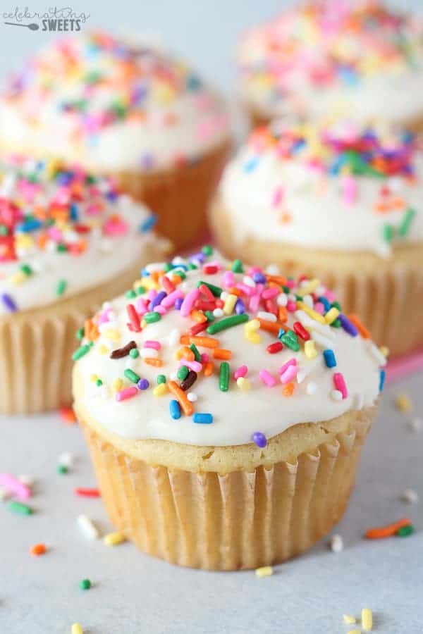 Vanilla cupcakes with vanilla ice cream and rainbow sprinkles.