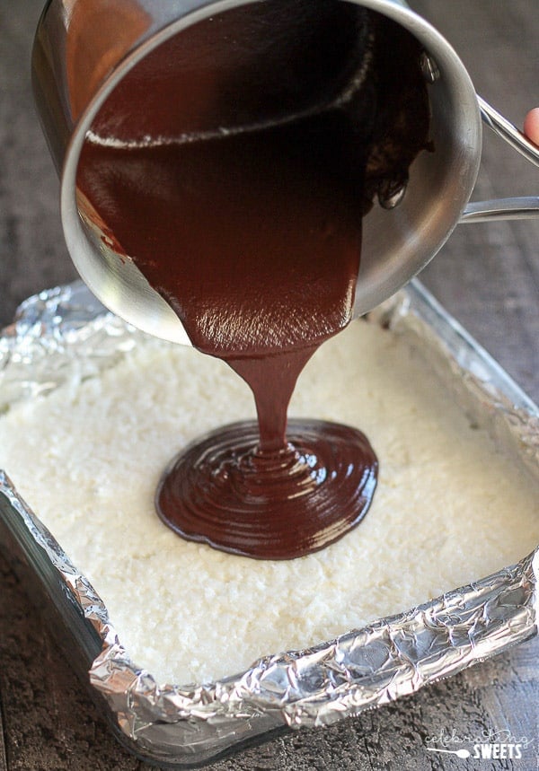 Ganache being poured over a pan of coconut brownies.