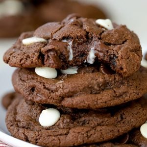 Three chocolate cookies stacked on a white plate.