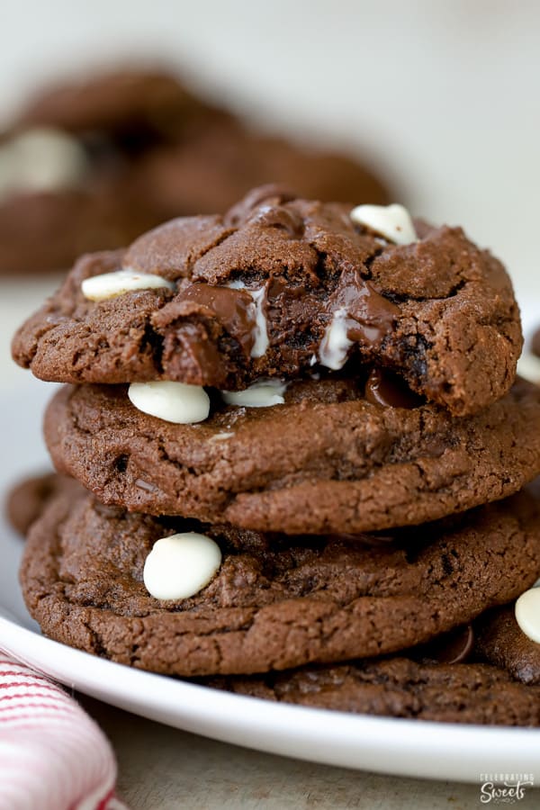 Three chocolate cookies stacked on a white plate.