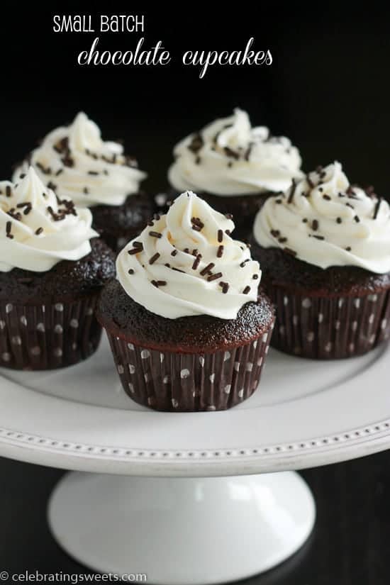 Chocolate cupcakes topped with vanilla frosting and chocolate sprinkles on a white platter.