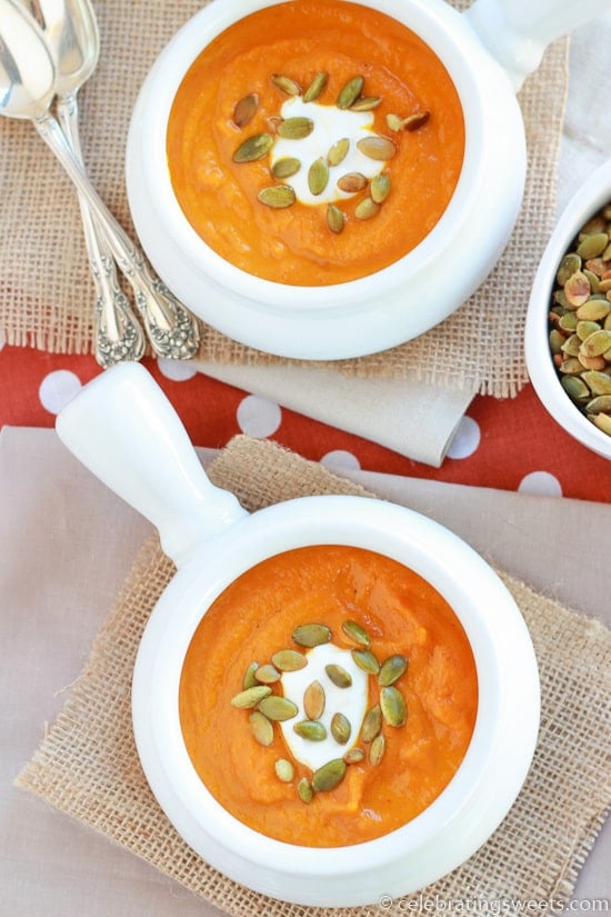 Butternut squash soup in two white bowls topped with pumpkin seeds.