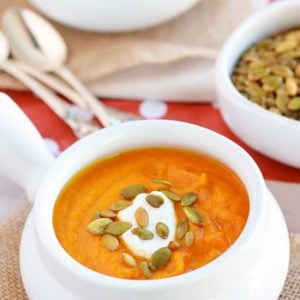 Butternut squash soup in a white bowl topped with pumpkin seeds.