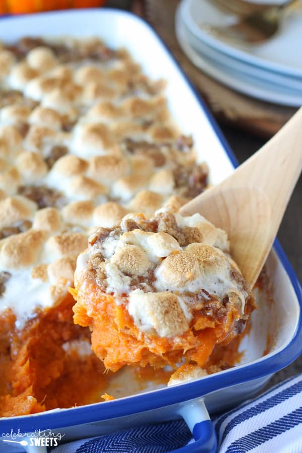 Sweet potato casserole topped with marshmallows on a wooden spoon. 
