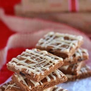 Stacks of gingerbread bars drizzled with icing on a piece of parchment paper.