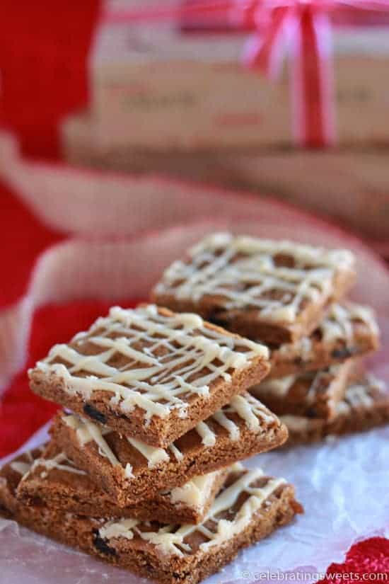 Stacks of gingerbread bars drizzled with icing on a piece of parchment paper.