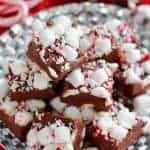 Slices of fudge on a silver plate topped marshmallows and crushed candy canes.