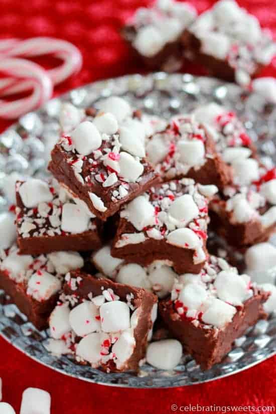 Slices of fudge on a silver plate topped marshmallows and crushed candy canes.