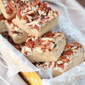 White chocolate fudge topped with pecans in a yellow box.