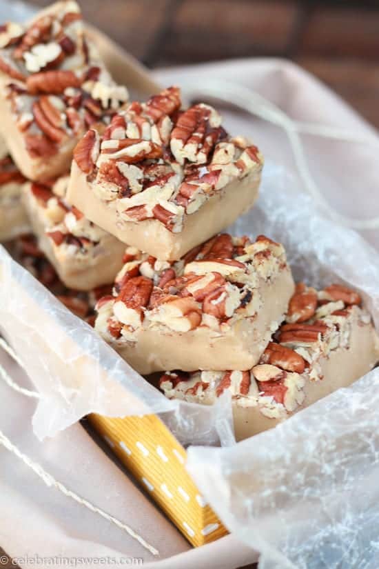 White chocolate fudge topped with pecans in a yellow box.
