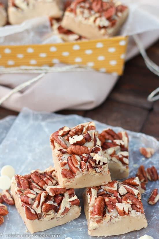 White chocolate fudge topped with pecans on parchment paper.