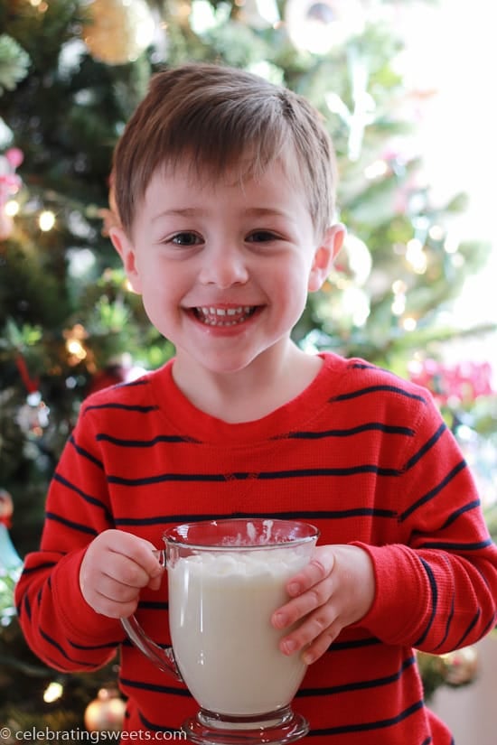 A little boy with a mug of white hot chocolate.