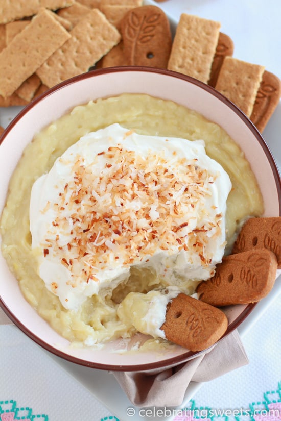 Bowl of coconut pie dip topped with whipped cream, toasted coconut and cookies.