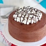 Round chocolate cake topped with marshmallows and chocolate sauce.