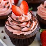 Chocolate cupcake topped with strawberry frosting and a heart shaped strawberry.