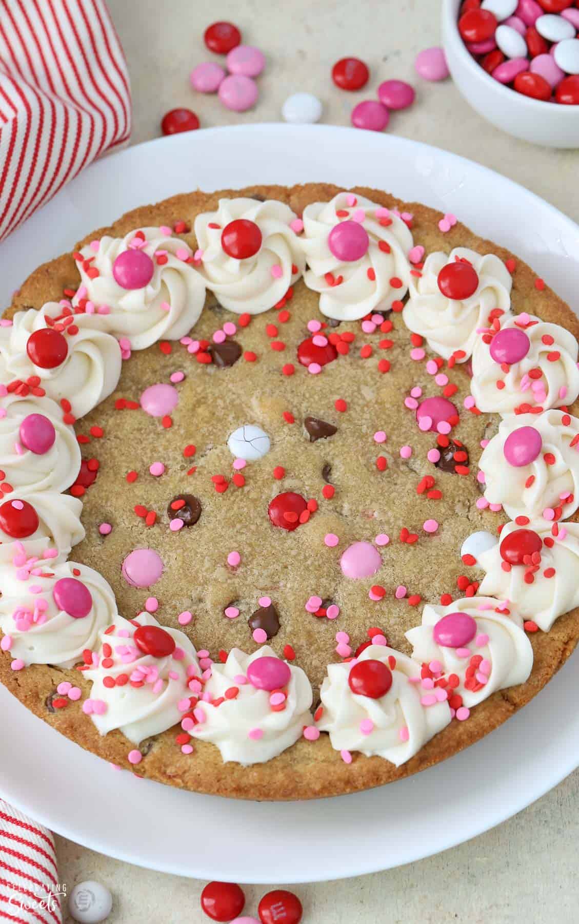 Cookie cake topped with frosting and red and pink M&M's