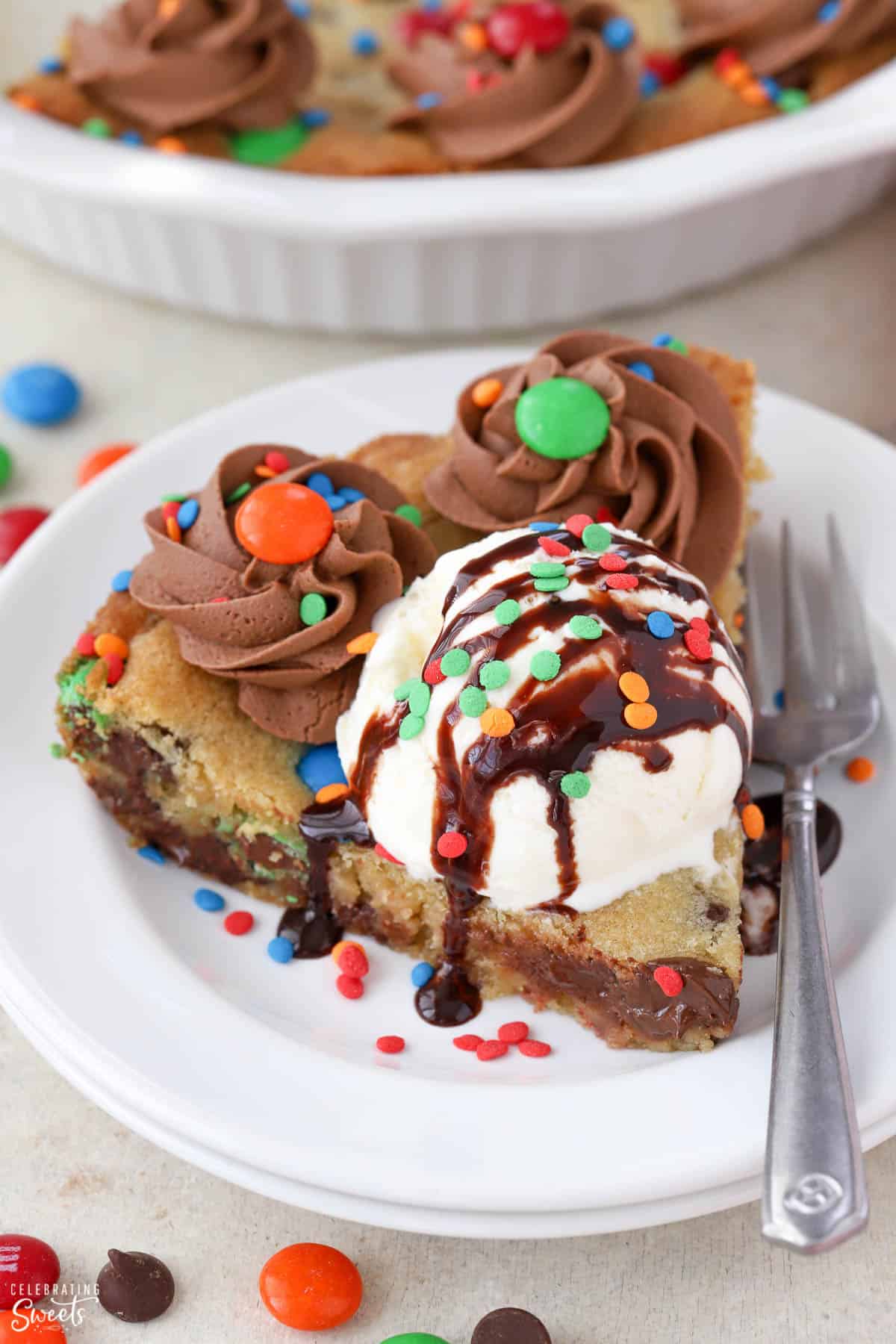 Slice of chocolate chip cookie cake topped with ice cram and hot fudge sauce