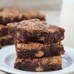 Stack of three peanut brownies on a plate.