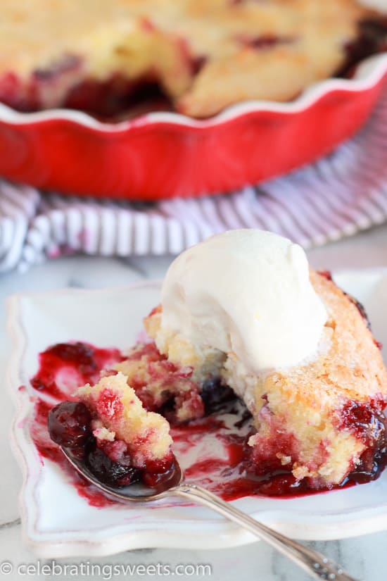 Berries topped with cake and a scoop of ice cream on a white plate.