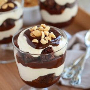 Glass trifle dish with layers of brownies, whipped cream, and fudge.