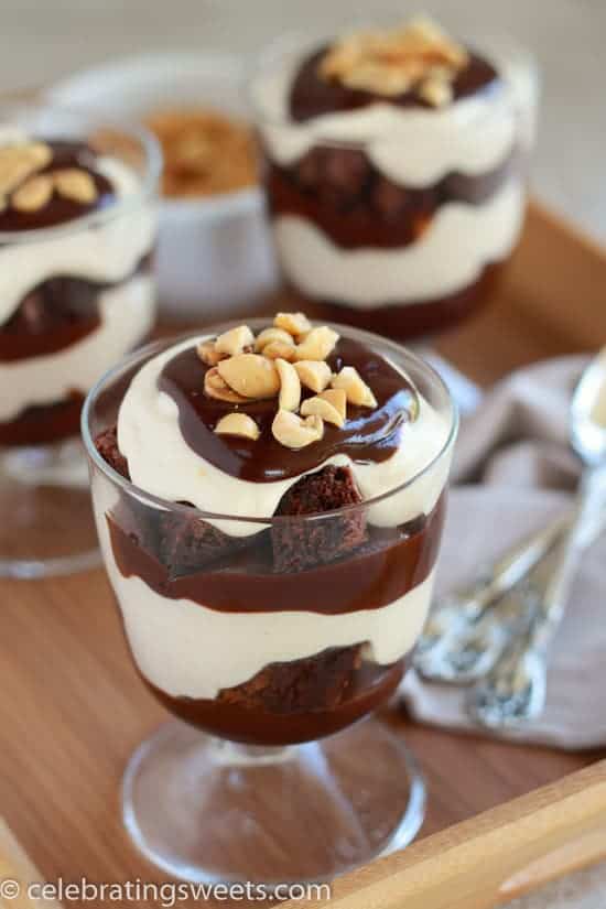 Glass filled with layers of brownies, whipped cream, and fudge sauce.