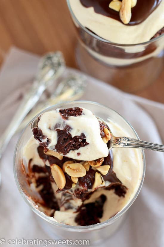 Glass with layers of brownies, whipped cream, and fudge sauce.