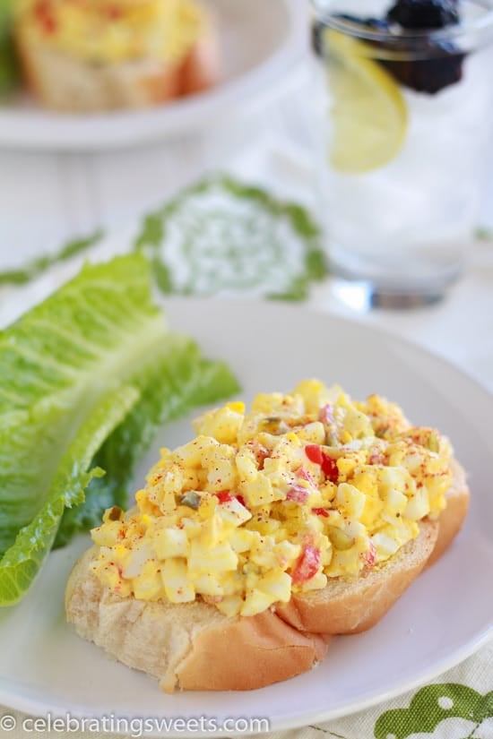 Egg salad on a piece of bread on a white plate.