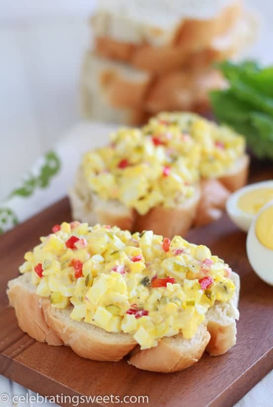 Egg salad on a piece of bread on a wooden board. 
