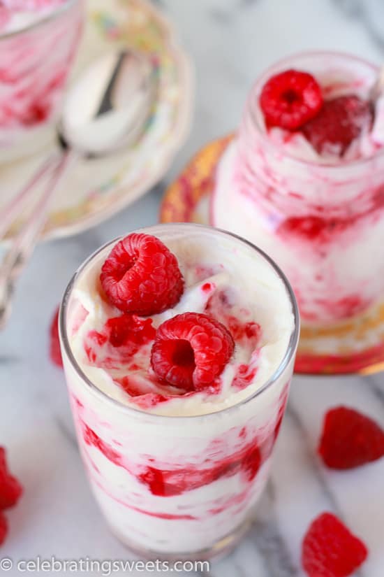 Glass filled with layers of whipped cream and raspberries.