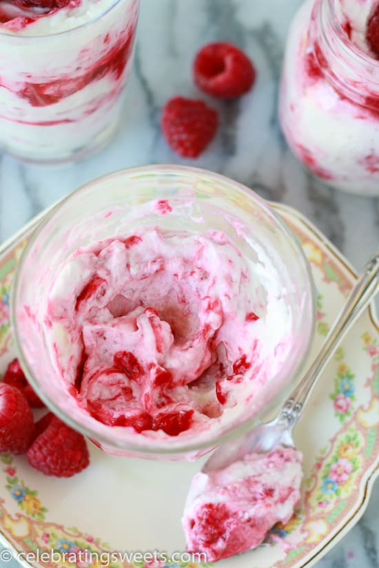 Glass filled with layers of whipped cream and raspberries.