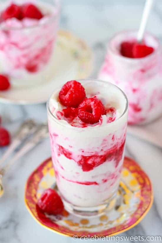 Glass filled with layers of whipped cream and raspberries. 